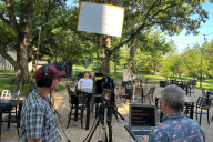 A crew films as a student sits at a table with a tablet on the Saint Mary's College campus.